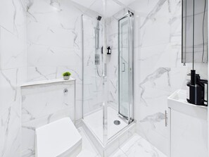 A modern bathroom with a glass-enclosed shower, a white toilet, and a sink with a black faucet. - Be London - The Hampstead Residences (Greater London)