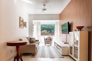 A living room with a sofa, a small table, a television, and a cabinet. - 3-Bedroom Spacious and Charming Apartment with Nature Views (Vila Velha)