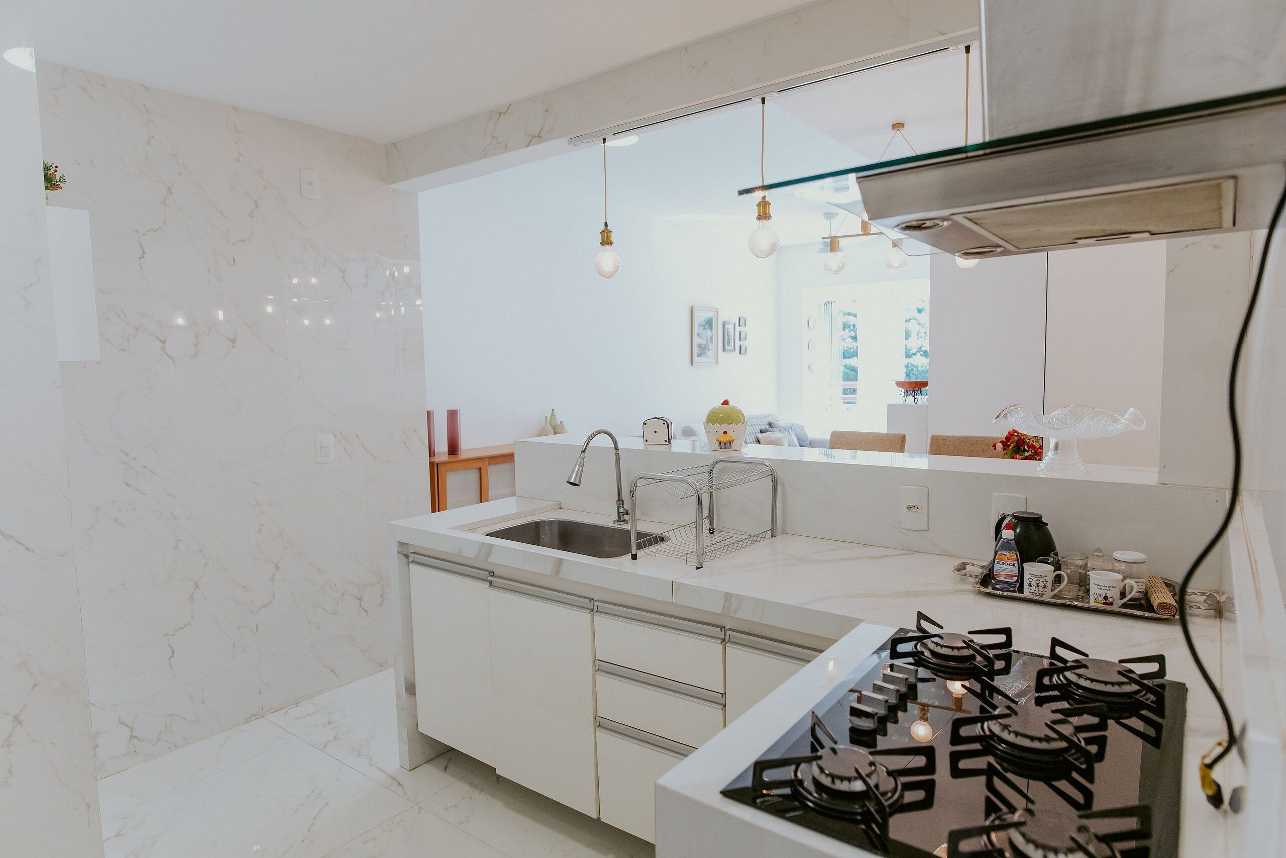A modern kitchen with a gas stove, stainless steel sink, and marble backsplash.