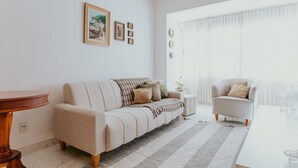 A living room with a sofa, armchair, and a table. - 3-Bedroom Spacious and Charming Apartment with Nature Views (Vila Velha)