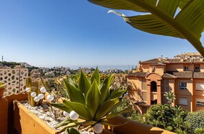 Ein Balkon mit einer Kakteenpflanze, weißen Papierlanternen und Blick auf Küstengebäude.