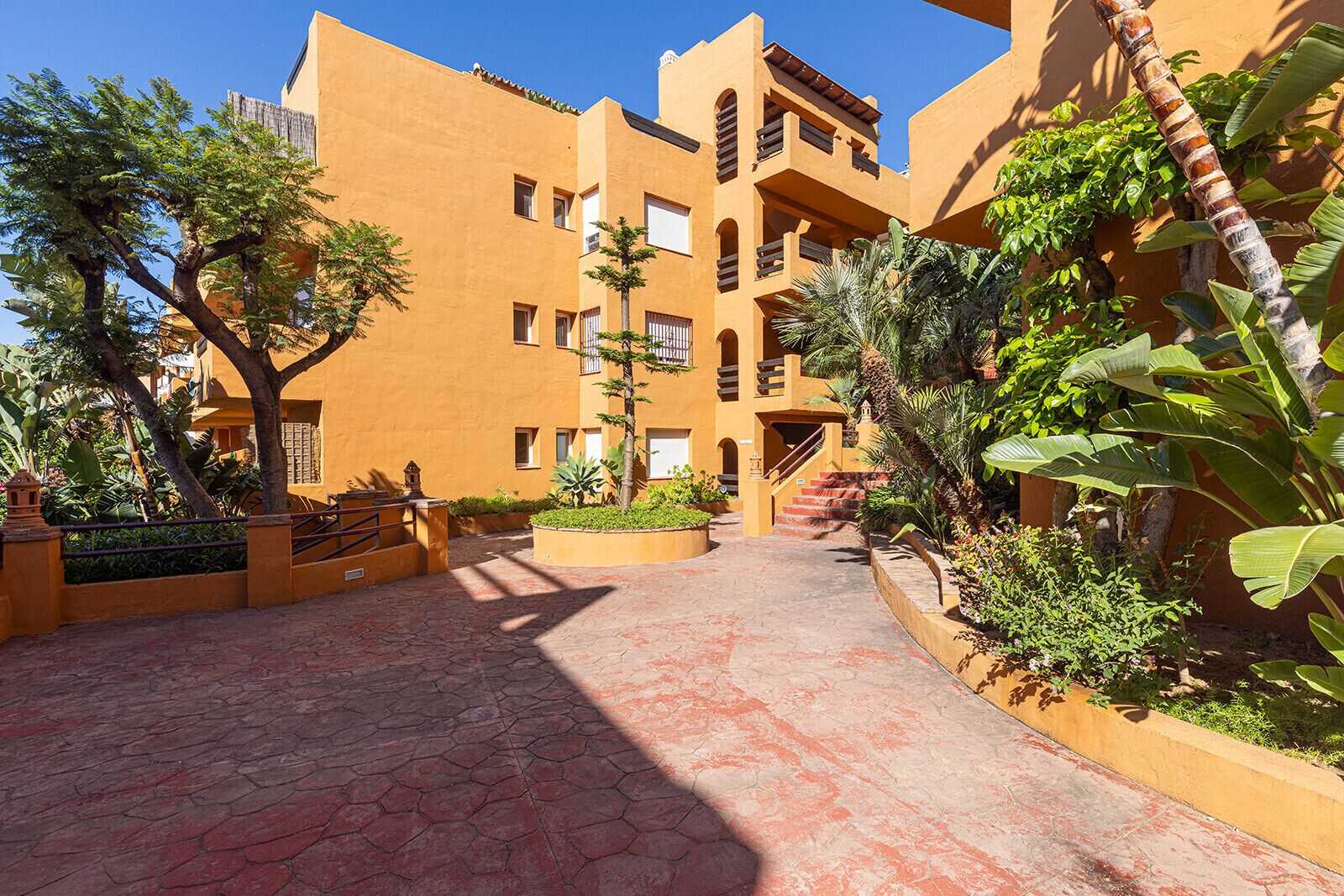 Un patio con un sendero empedrado, rodeado de edificios con balcones y ventanas.