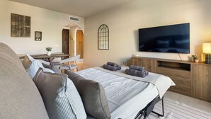 Ein Hotelzimmer mit Bett, Fernseher, Schreibtisch und Stuhl.