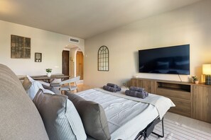 Ein Hotelzimmer mit Bett, Fernseher, Schreibtisch und Stuhl.