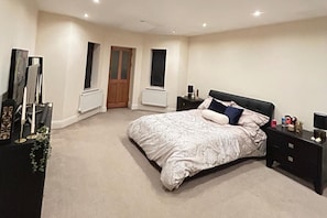 A bedroom with a large bed, bedside tables, a dresser, and a mirror.