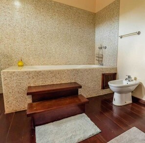 Un baño con bañera, lavamanos y un banco de madera.