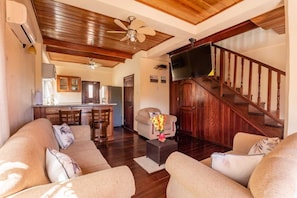 A living room with a sofa, a coffee table, a TV, and a staircase.