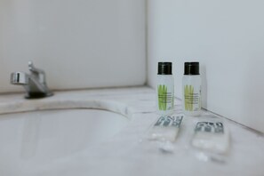 Zwei Flaschen Shampoo und Conditioner auf einem weißen Waschbecken mit Wasserhahn.