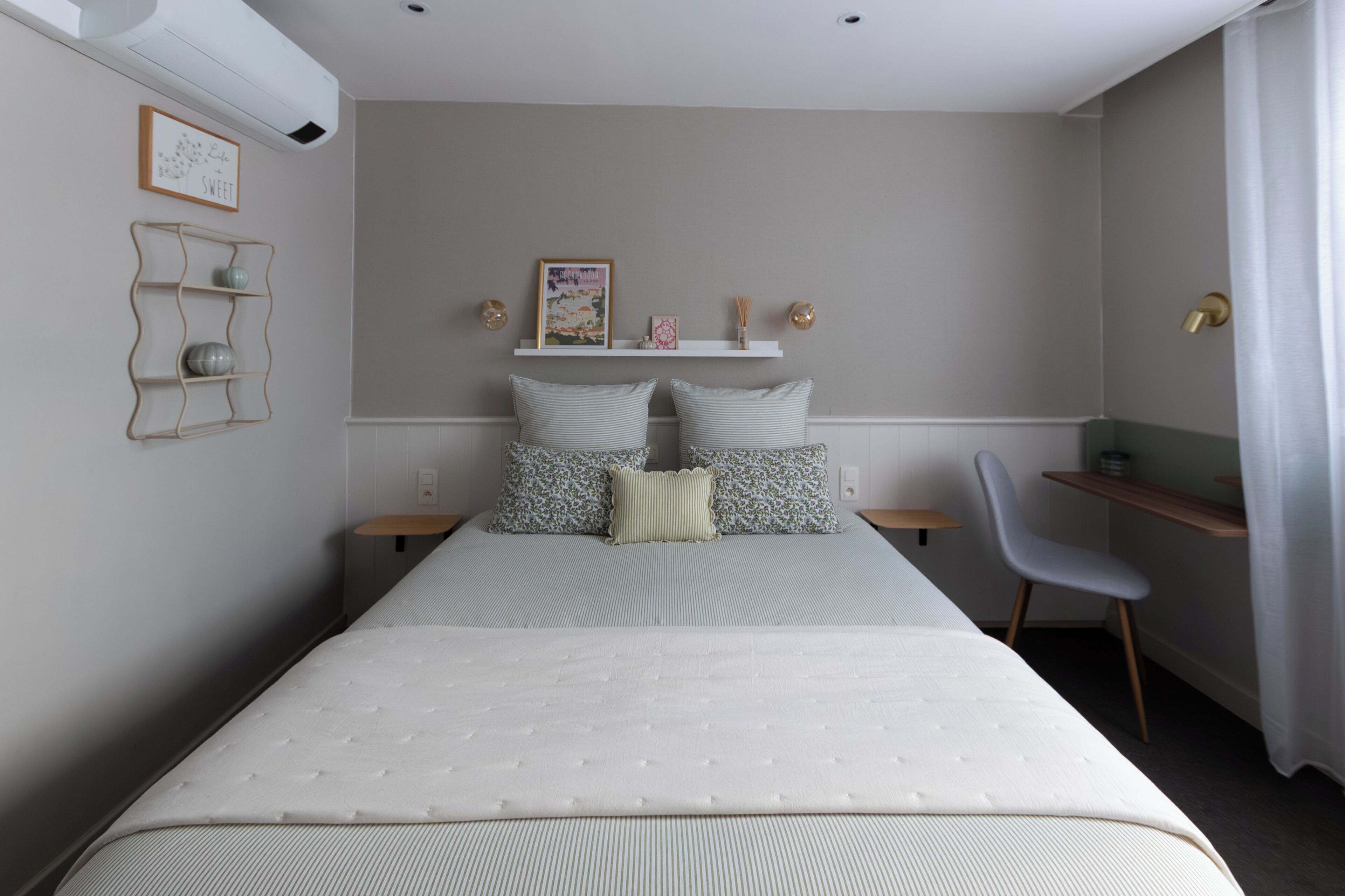 A neatly arranged bedroom with a bed, bedside tables, a chair, and wall-mounted shelves.