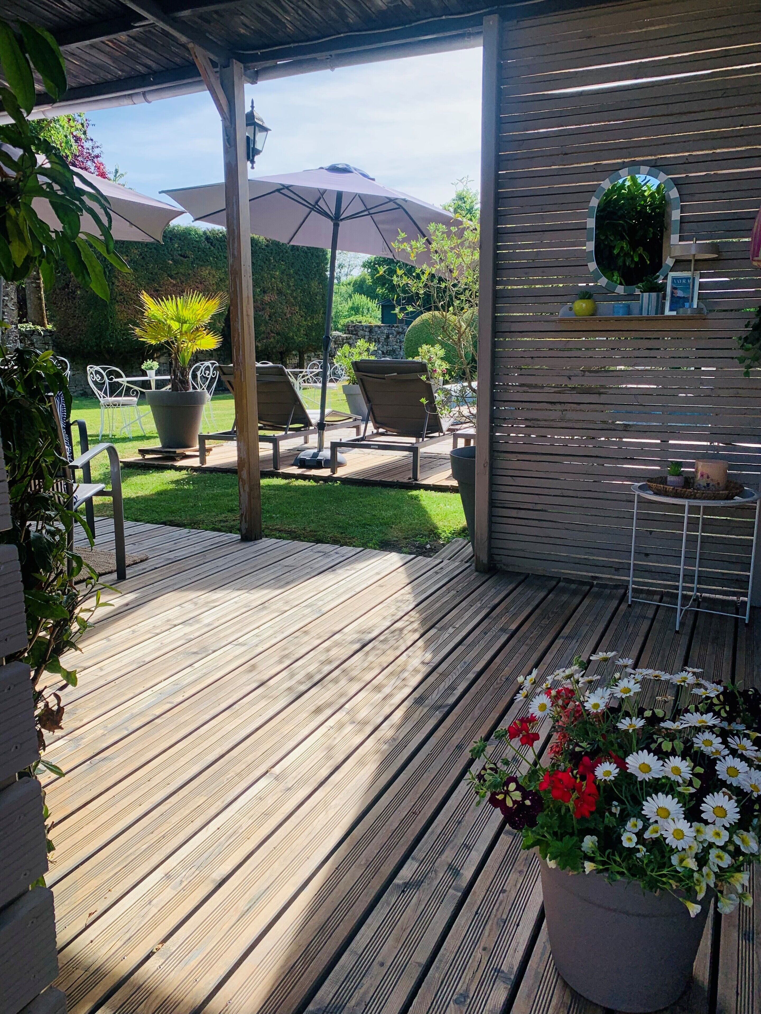 A wooden deck with outdoor furniture, a potted plant, and a garden view.