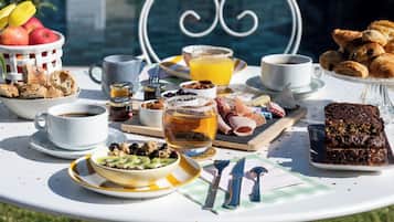 A breakfast table with various food items, a cup of coffee, and a bowl of fruit.