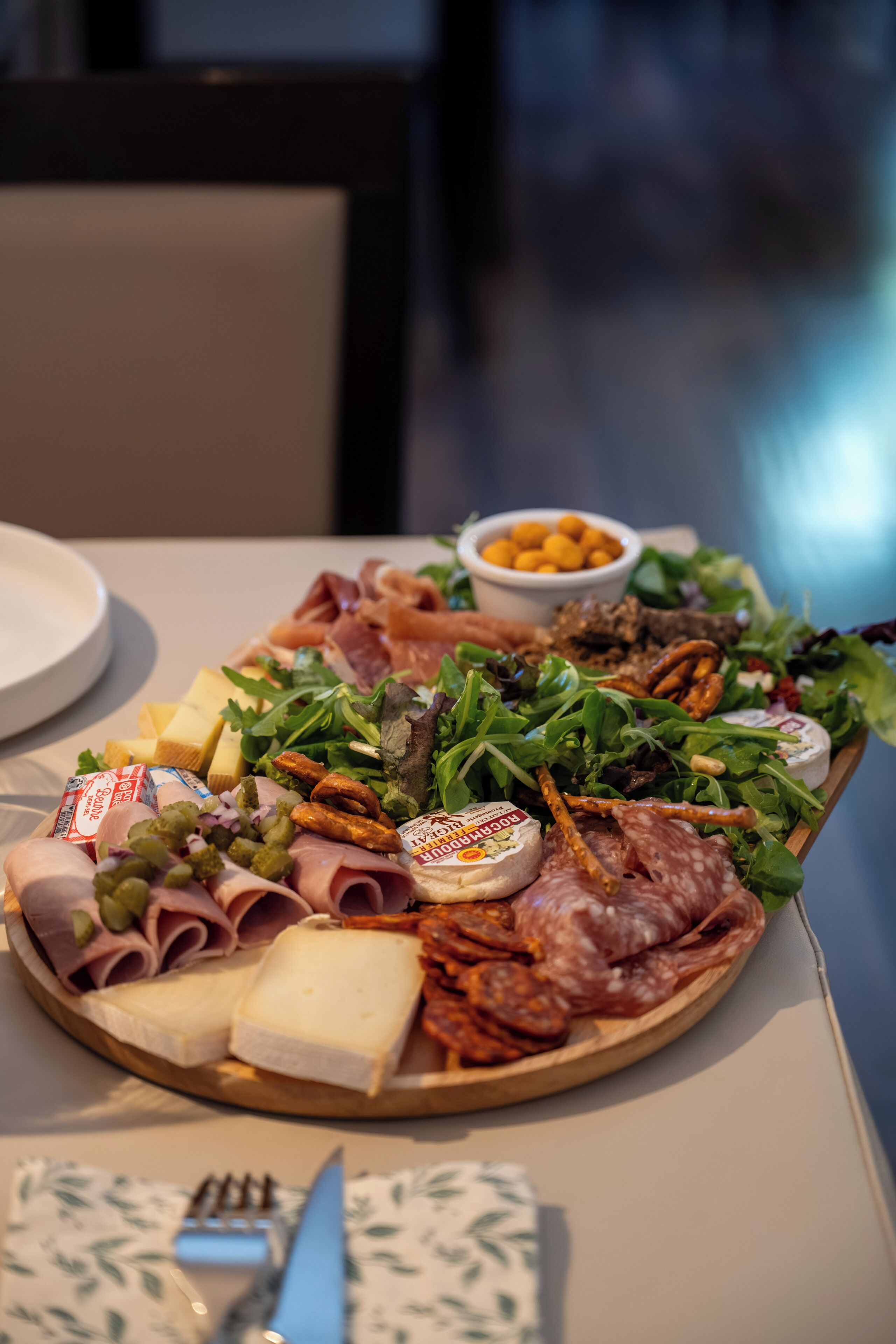 A charcuterie board with various meats, cheeses, and vegetables.