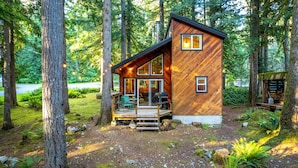 A cabin with a deck, large windows, and a chimney. - Barrel sauna, cedar cabin, woodstove (Deming)