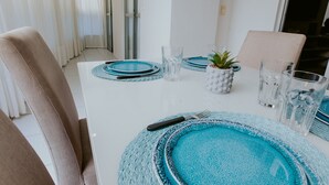 Una mesa de comedor dispuesta con individuales azules, vasos transparentes y una pequeña planta en maceta.