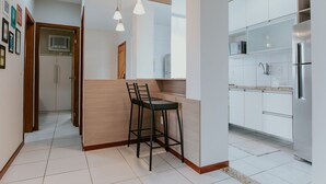 Una cocina moderna con armarios blancos, un refrigerador de acero inoxidable y una isla de madera con un taburete.