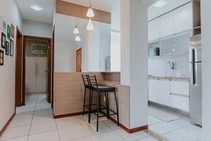 Eine moderne Küche mit weißen Schränken, einem Edelstahlkühlschrank und einer Holzinsel mit Barhocker.