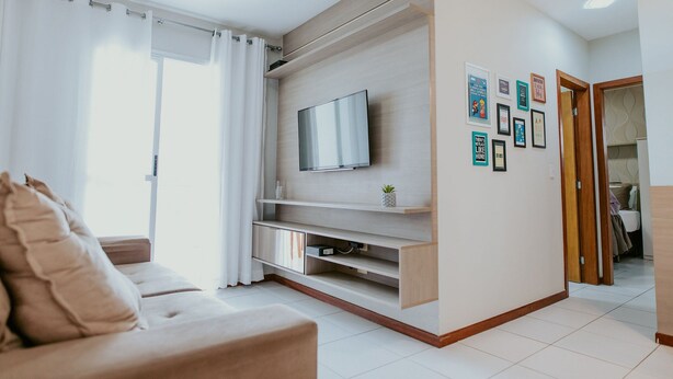 Una sala moderna con sofá, televisor y estanterías en la pared.
