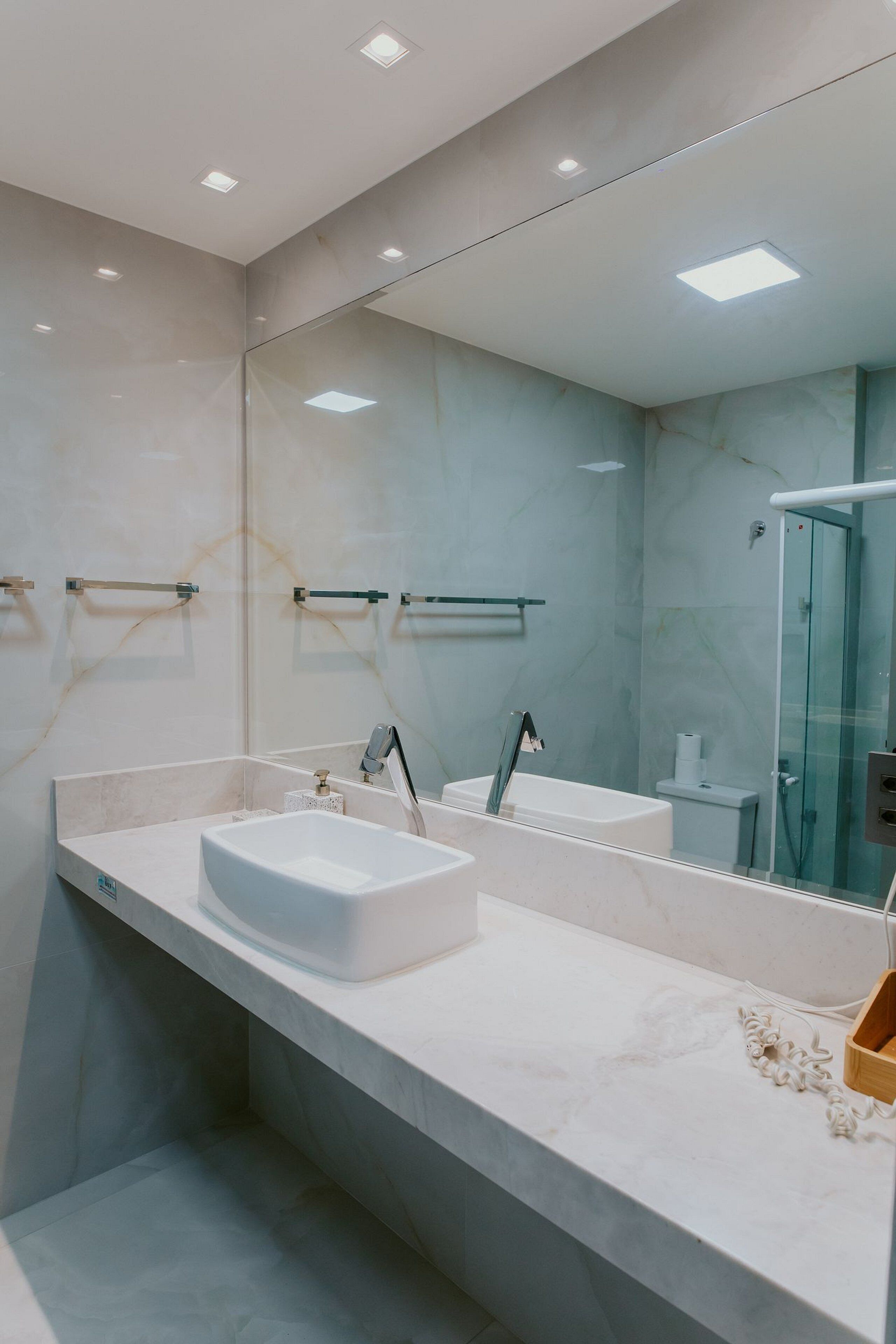 Ein modernes Badezimmer mit großem Spiegel, zwei Waschbecken und einer Duschkabine aus Glas.