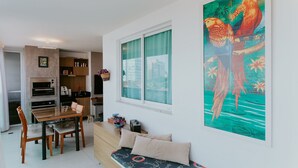 Eine moderne Küche mit integriertem Backofen, einem Esstisch mit Stühlen, einer Bank mit Kissen und einem großen Fenster mit Vorhängen.