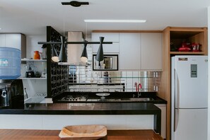 Une cuisine moderne avec un plan de travail noir, des appareils en acier inoxydable et des armoires en bois.