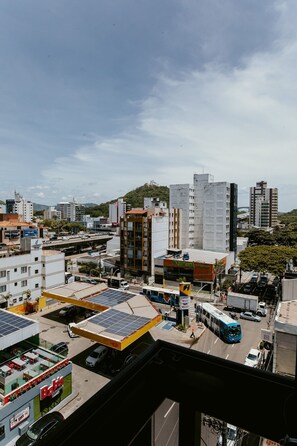 A cityscape with buildings, a bus, and a solar panel installation. - Cozy Steps from the Sea | Costa Beach (Vila Velha)