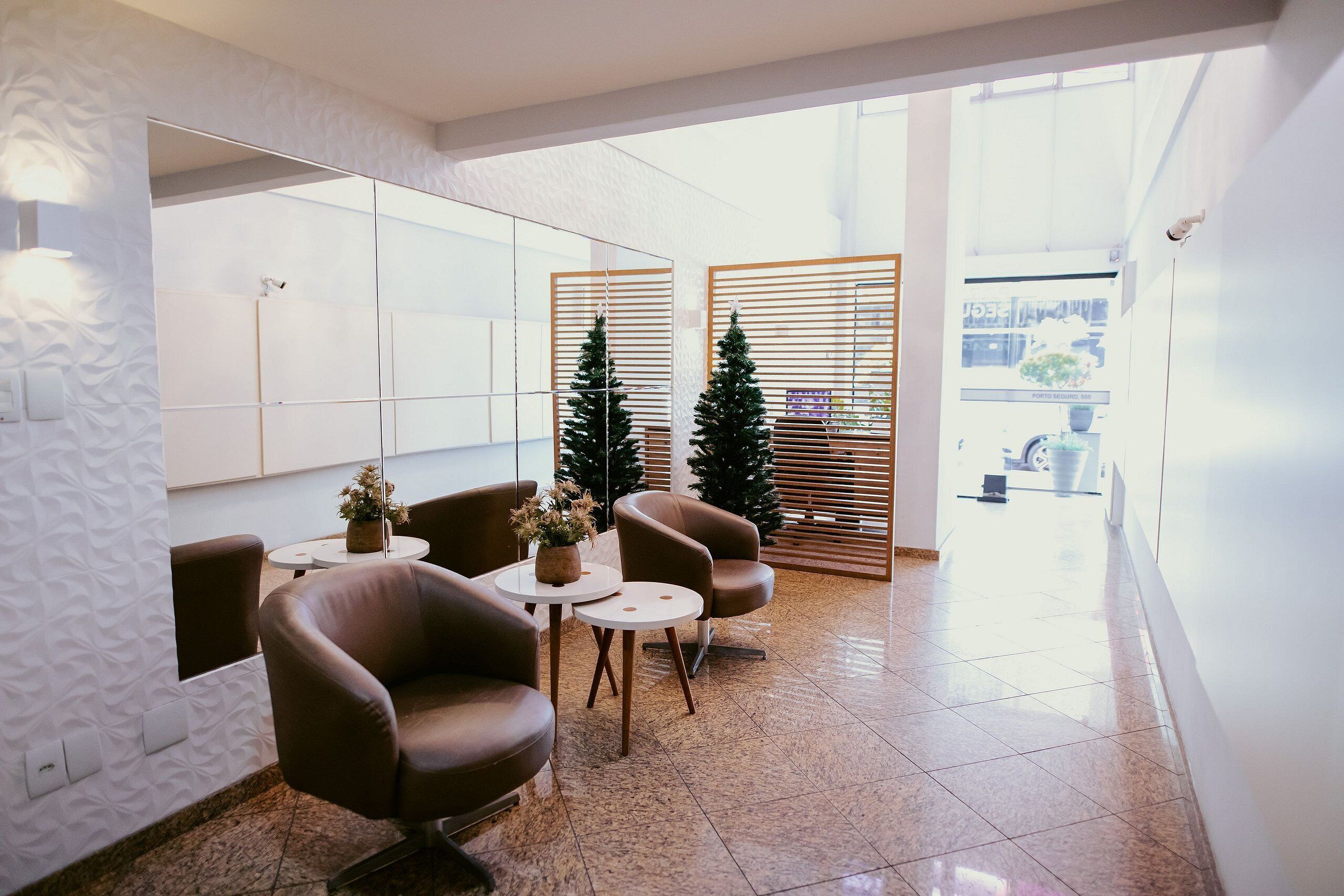 Un lobby moderno con sillones de cuero, una pequeña mesa con una planta y un árbol de Navidad.