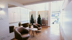 En modern entréhall med läderfåtöljer, ett litet bord med en växt och en julgran.