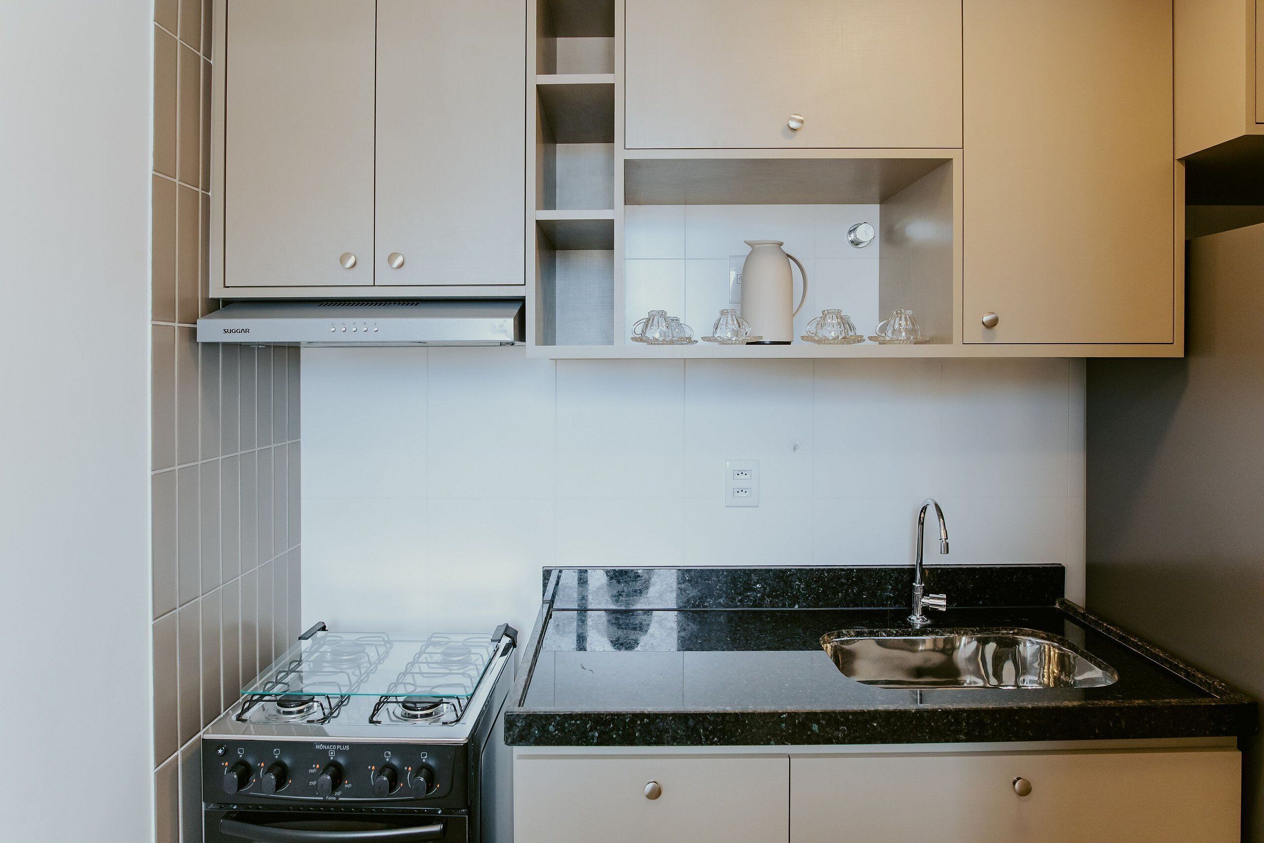 A kitchen with a gas stove, oven, stainless steel sink, and white cabinetry.