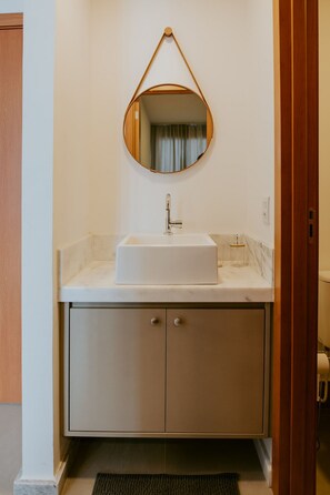 Ein Badezimmer mit einem weißen Waschbecken, einem Spiegel und einem Schrank.