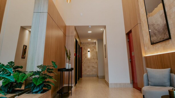 Un moderno vestíbulo de hotel con un mostrador de recepción de madera, una zona de estar y un pasillo que conduce a otras habitaciones.