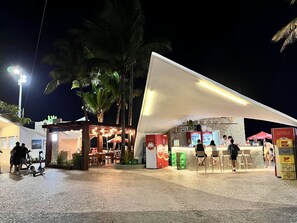 Ein Außenbereich mit Tischen, Stühlen, einer Kiosk und einer überdachten Sitzgelegenheit.