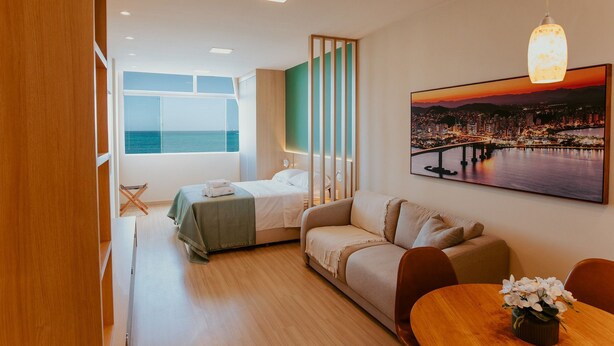 Een moderne hotelkamer met een bed, een bank, een eettafel en een stadsgezicht schilderij.