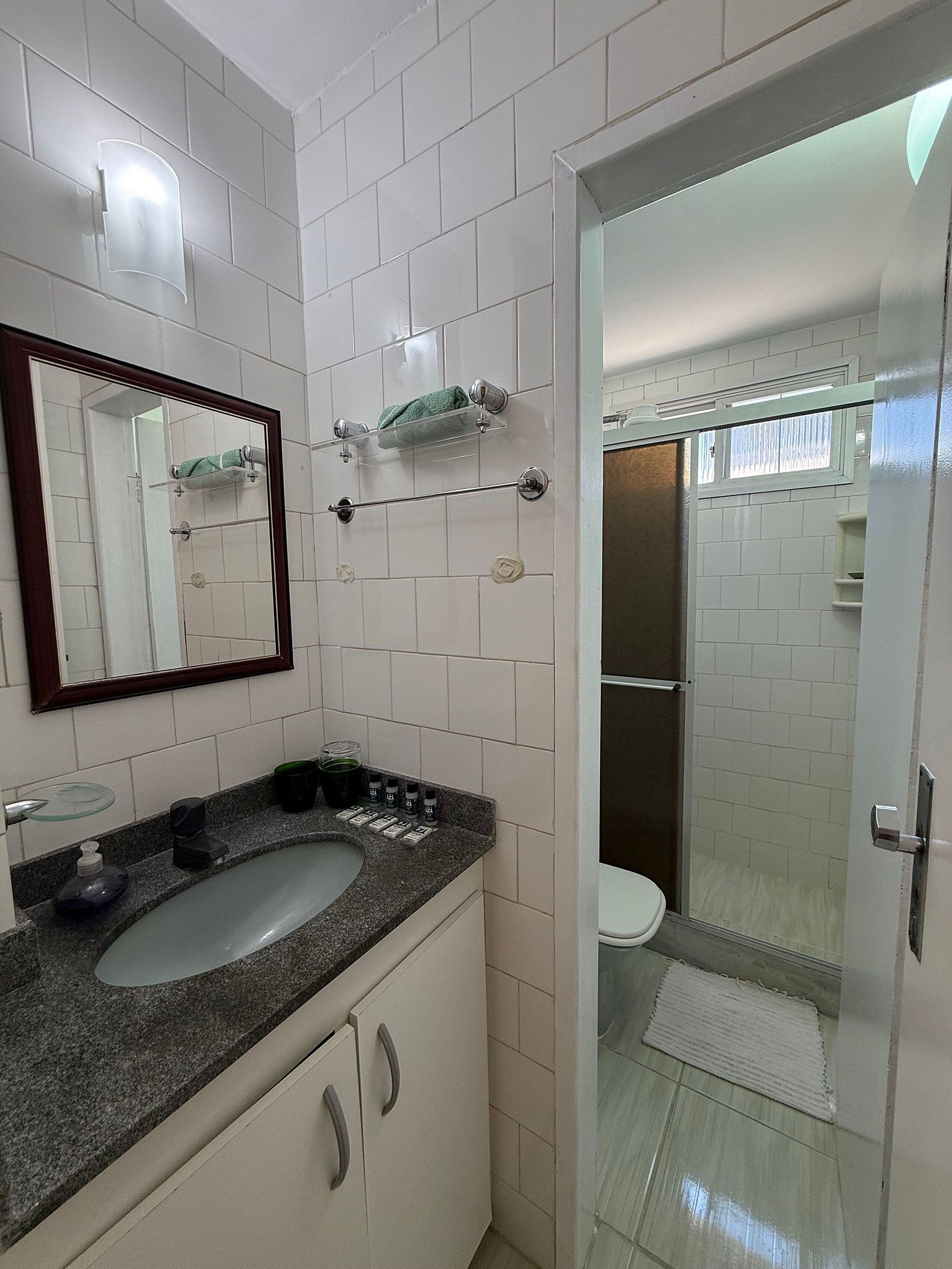 Ein Badezimmer mit Waschbecken, Spiegel, Handtuchhalter und Duschbereich.