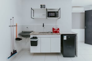 Eine kompakte Küche mit Mikrowelle, Spüle und kleinem Kühlschrank.