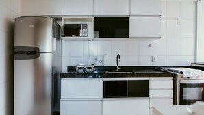 Una cucina moderna con elettrodomestici in acciaio inossidabile, mobili bianchi e un piano di lavoro nero.