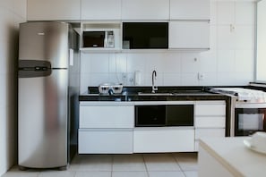 Eine moderne Küche mit Edelstahlgeräten, weißen Schränken und einer schwarzen Arbeitsplatte.