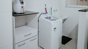 Een moderne badkamer met een wasmachine, een wastafel en een spiegel.