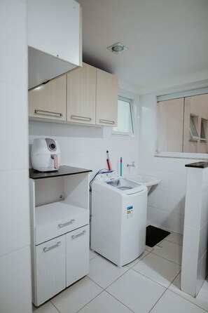 A modern bathroom with a washing machine, a sink, and a mirror. - 2-bedroom apartment with the best location in Guarapari. (Guarapari)