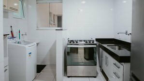 Een kleine keuken met een wasmachine, een fornuis en een spoelbak.