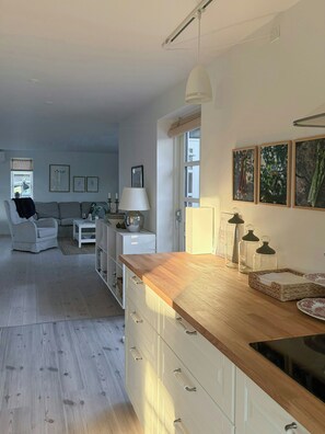 Eine moderne Küche mit Holzarbeitsplatten, einem eingebauten Backofen und einem Essbereich mit Sofa und Tisch.