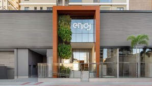 Un edificio moderno con una amplia fachada de vidrio, un jardín vertical y un cartel que dice 'enjoy residence by Let Plaza 745'.