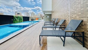 Zona de piscina en la azotea con sillones y vistas al horizonte de la ciudad.