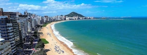 A coastal cityscape with a prominent mountain, high-rise buildings, and a beach. - Cozy Studio at Enjoy Itapoã (Vila Velha)