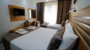 Habitación de hotel con dos camas, un escritorio, una silla, un televisor y una ventana con cortinas.