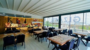 Un restaurante con una decoración moderna, paredes revestidas de madera, un bufé con diversas opciones de comida y mesas con sillas.