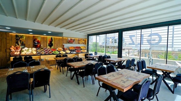 Restaurante com decoração moderna, paredes revestidas de madeira, um buffet variado e mesas com cadeiras.