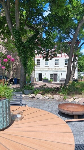 A building with a white facade and red trim, surrounded by trees and greenery. - Holiday Apartment Henry – A Break Beneath Historic Beams (Arnstadt)
