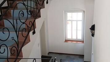 Una escalera con barandillas de metal decoradas, un ventanal con vistas y un suelo de baldosas.