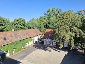 A residential area with a paved driveway, a house with a sloped roof, and a tree. - Holiday Apartment Henry – A Break Beneath Historic Beams (Arnstadt)