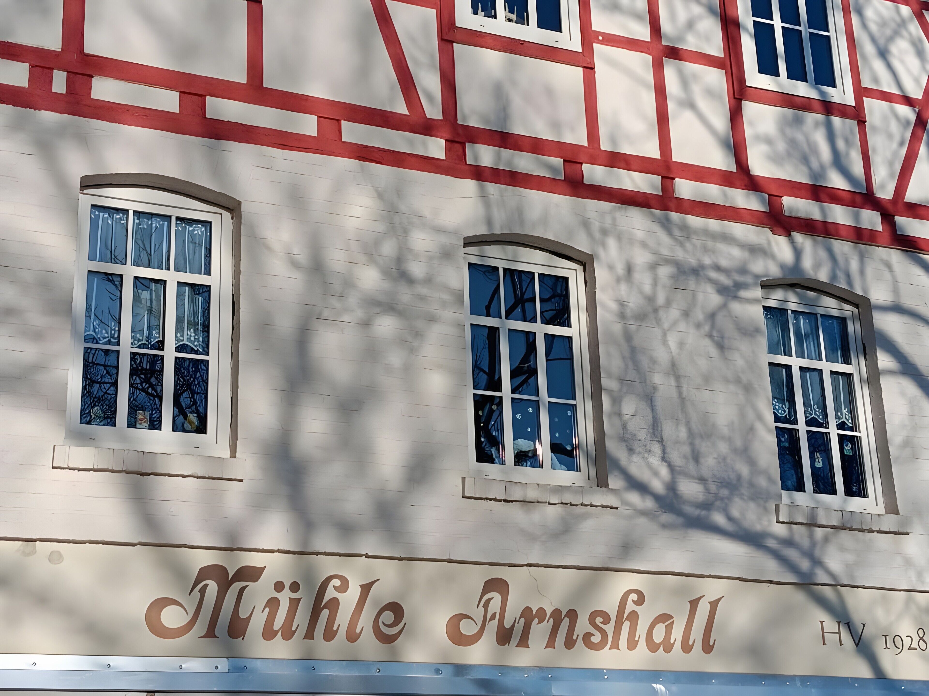 A building with the name 'Mühle Arnshall' and the year '1928' on its facade.